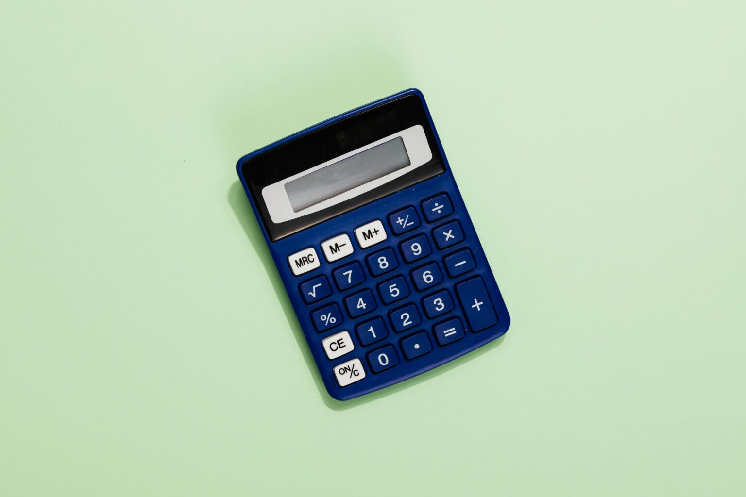 A blue calculator placed on a light green background. Ideal for financial and educational themes.