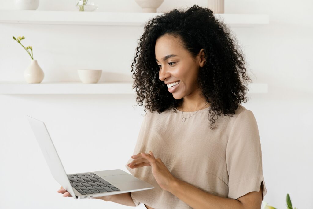 Smiling woman working on a laptop in a modern home office, highlighting freelance lifestyle.